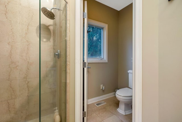 bathroom featuring tiled shower, tile patterned floors, and toilet