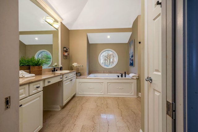 bathroom with vanity, lofted ceiling, and a tub