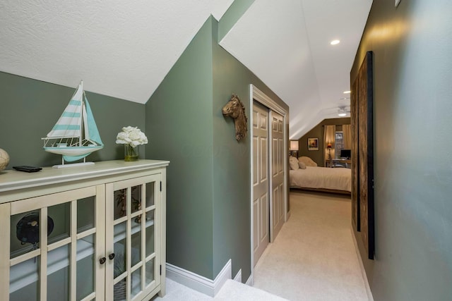 hall featuring lofted ceiling and light carpet