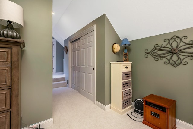 hallway featuring lofted ceiling and light carpet