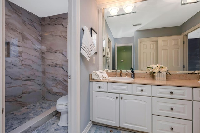 bathroom featuring vanity, toilet, and a tile shower