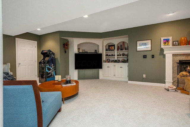 living room featuring built in shelves, light colored carpet, and a fireplace