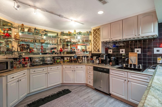 kitchen with sink, light hardwood / wood-style flooring, ornamental molding, and appliances with stainless steel finishes