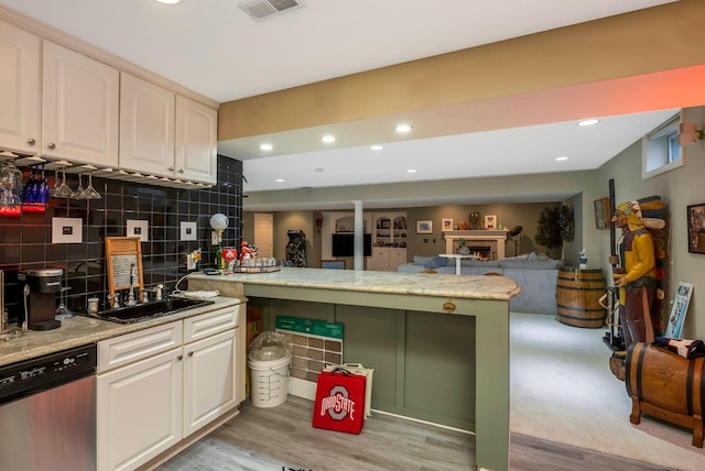 kitchen with kitchen peninsula, decorative backsplash, stainless steel dishwasher, and light hardwood / wood-style floors