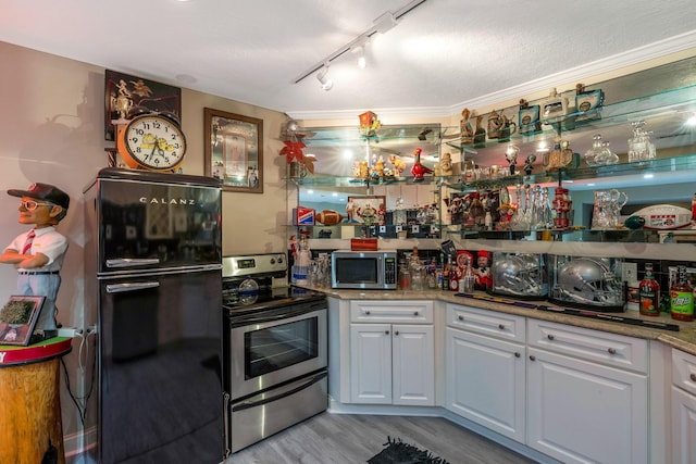 kitchen featuring light stone counters, stainless steel appliances, crown molding, white cabinets, and light hardwood / wood-style floors