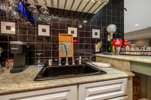 kitchen featuring decorative backsplash, white cabinetry, tile walls, and sink