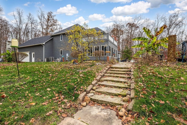 back of property featuring a sunroom, a yard, and a balcony