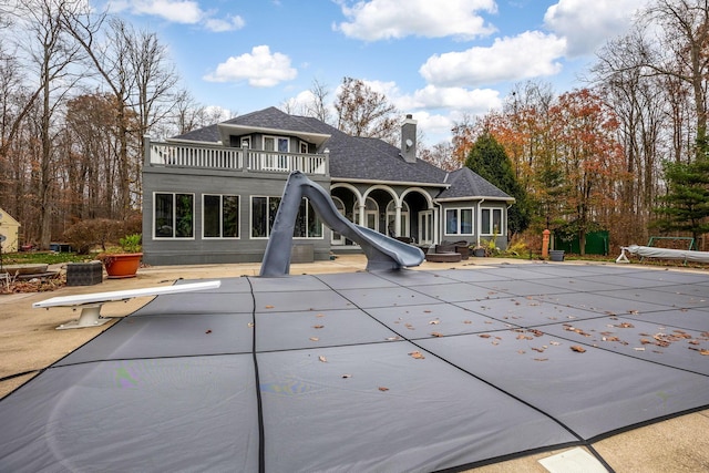 back of house featuring a patio area, a balcony, and a covered pool