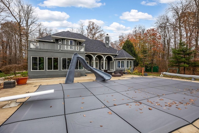 rear view of property with a balcony, a covered pool, and a patio area