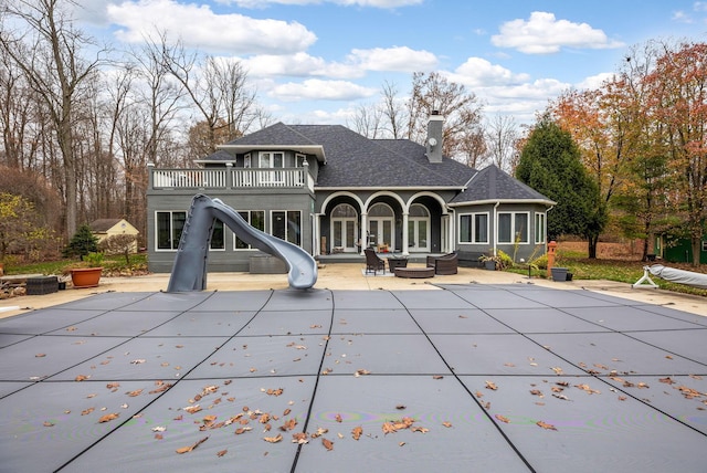 rear view of property with an outdoor hangout area, a balcony, a covered pool, and a patio area