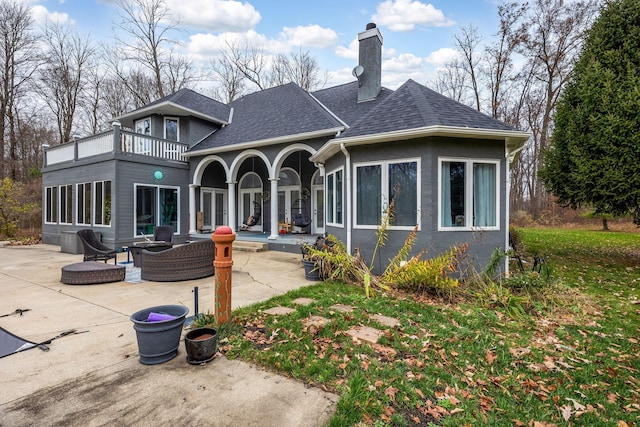 back of house featuring outdoor lounge area, a balcony, and a patio