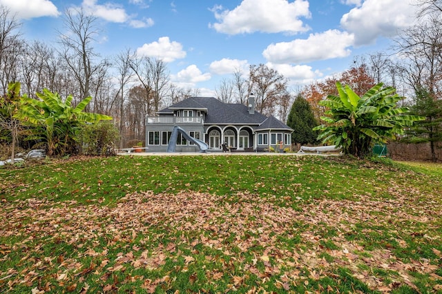 rear view of property with a lawn, a balcony, and a patio