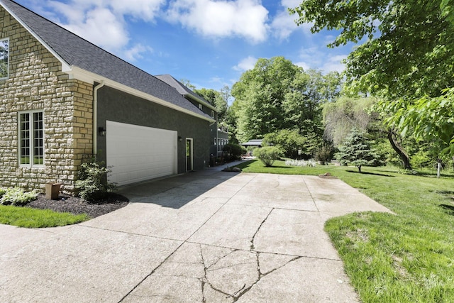 6003 Nichols Ln, Johnstown, OH 43031 - view of side of home with stone siding, a shingled roof, concrete driveway, a lawn, and an attached garage