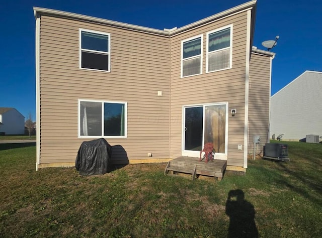 rear view of house with central AC unit and a yard