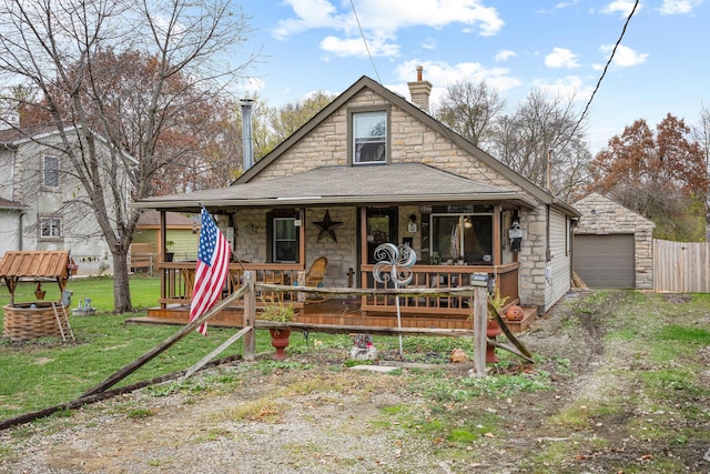 view of front of home featuring a porch, a garage, an outdoor structure, and a front yard