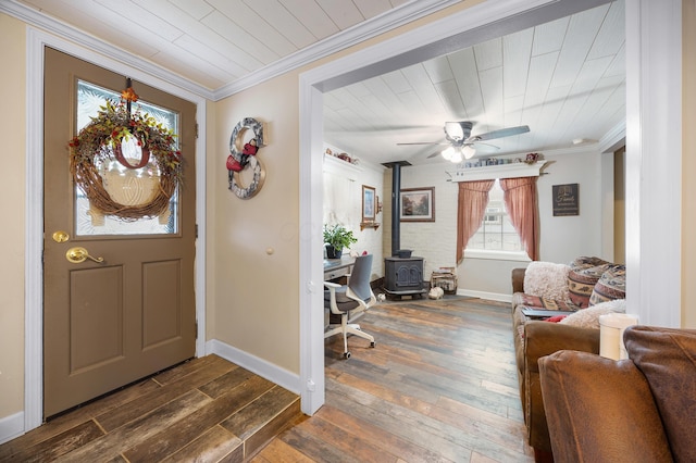 foyer entrance featuring a wood stove, ceiling fan, dark wood-type flooring, and crown molding