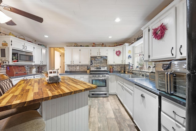 kitchen featuring butcher block counters, sink, light wood-type flooring, appliances with stainless steel finishes, and white cabinetry