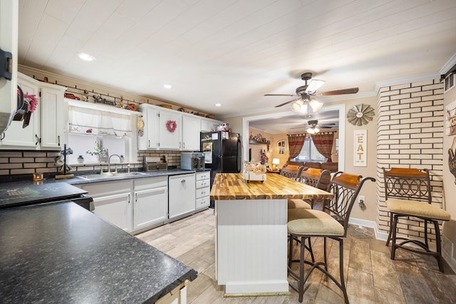 kitchen featuring a breakfast bar area, white cabinetry, sink, and light hardwood / wood-style flooring