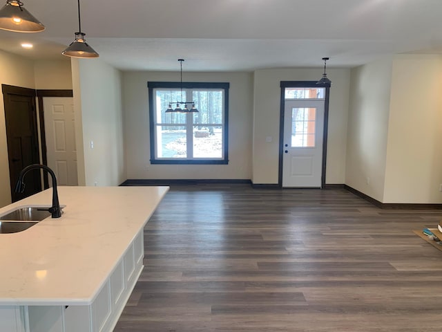 kitchen with dark hardwood / wood-style flooring, light stone counters, sink, and decorative light fixtures