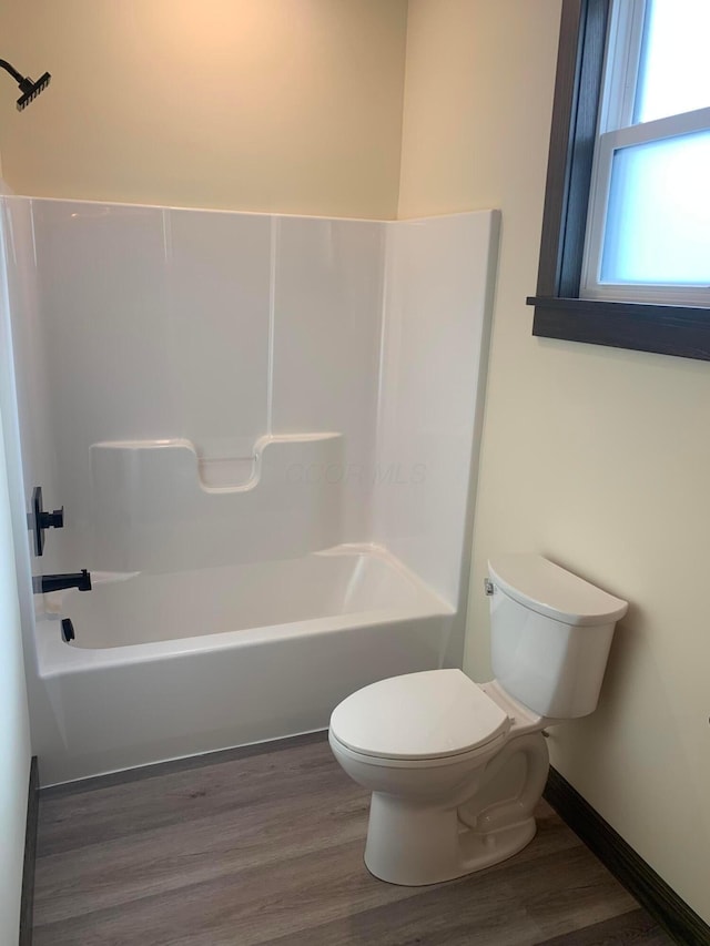 bathroom with hardwood / wood-style flooring, toilet, and shower / bath combination