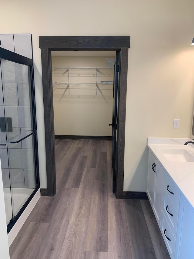 bathroom with hardwood / wood-style flooring, vanity, and walk in shower