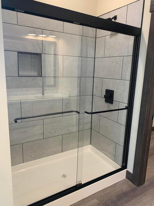 bathroom with a shower with shower door and wood-type flooring