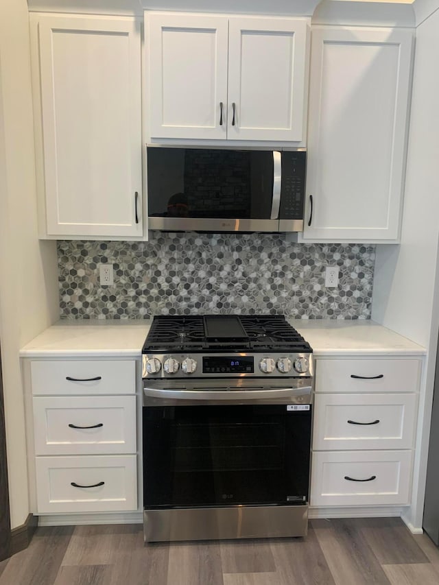 kitchen with white cabinets, appliances with stainless steel finishes, and wood-type flooring