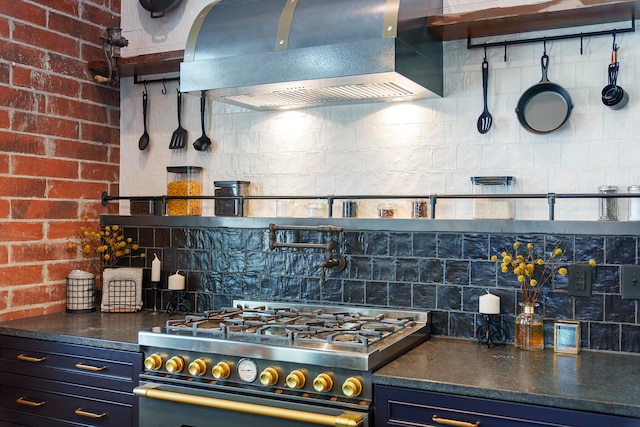 kitchen with brick wall, decorative backsplash, stainless steel range with gas cooktop, and wall chimney range hood