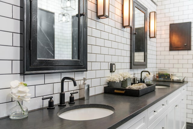 kitchen featuring white cabinets, backsplash, sink, and tile walls