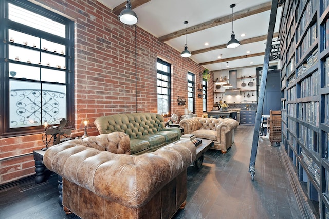 living room with beam ceiling, dark hardwood / wood-style flooring, brick wall, and a high ceiling