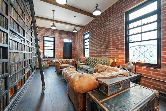 living room featuring beamed ceiling, dark hardwood / wood-style flooring, and brick wall