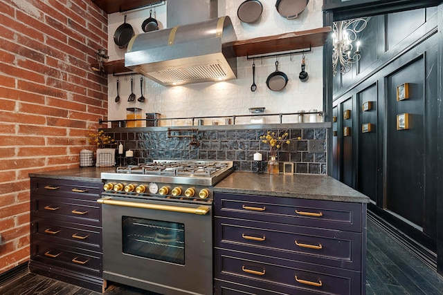 kitchen with backsplash, extractor fan, high end stainless steel range, and brick wall