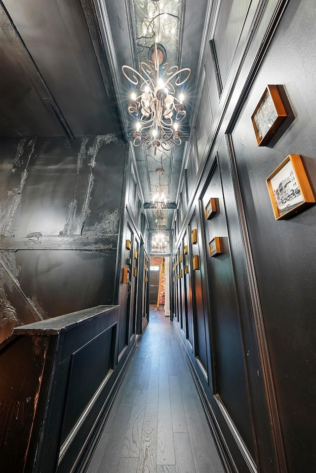 hall with dark hardwood / wood-style flooring, ornamental molding, and a chandelier