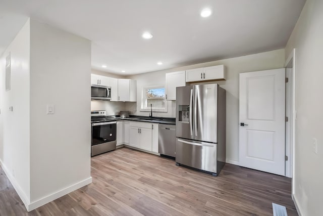 kitchen featuring white cabinets, sink, appliances with stainless steel finishes, and light hardwood / wood-style flooring