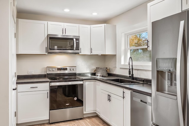 kitchen featuring white cabinets, appliances with stainless steel finishes, light hardwood / wood-style floors, and sink