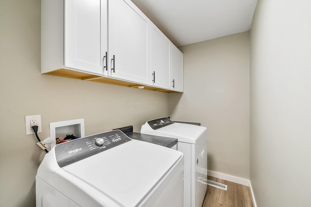 laundry room featuring independent washer and dryer, cabinets, and light wood-type flooring