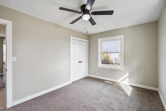 unfurnished bedroom featuring carpet floors, a closet, and ceiling fan