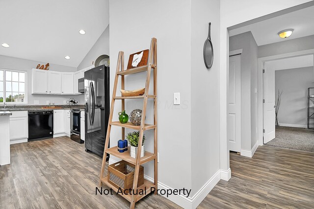 kitchen featuring hardwood / wood-style flooring, vaulted ceiling, white cabinets, and black appliances