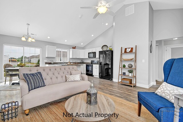 living room featuring high vaulted ceiling, sink, ceiling fan with notable chandelier, and light hardwood / wood-style flooring