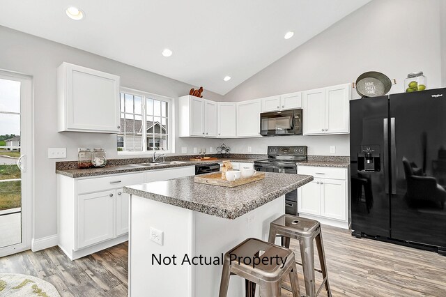 kitchen featuring a breakfast bar area, a kitchen island, white cabinetry, and black appliances