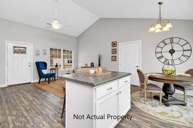 kitchen featuring white cabinetry, dark hardwood / wood-style flooring, vaulted ceiling, a kitchen island, and ceiling fan with notable chandelier