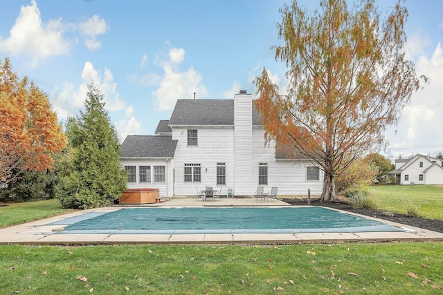 back of property featuring a lawn, a patio area, and a swimming pool with hot tub