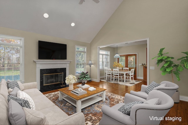 living room featuring a high end fireplace, a wealth of natural light, high vaulted ceiling, and wood-type flooring