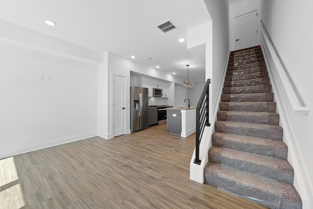 stairway featuring wood-type flooring and sink