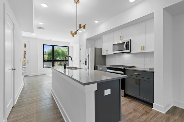 kitchen featuring gray cabinets, appliances with stainless steel finishes, sink, hanging light fixtures, and a kitchen island with sink