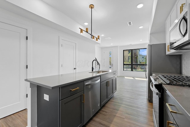 kitchen featuring sink, a center island with sink, appliances with stainless steel finishes, pendant lighting, and hardwood / wood-style floors