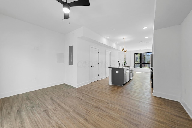 unfurnished living room with sink, hardwood / wood-style floors, electric panel, and ceiling fan