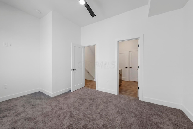 unfurnished bedroom with dark colored carpet, vaulted ceiling, and ceiling fan