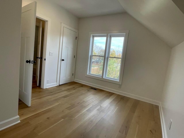 additional living space with vaulted ceiling and light hardwood / wood-style flooring