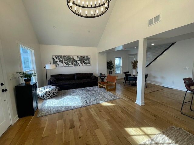 living room with wood-type flooring, high vaulted ceiling, and a notable chandelier